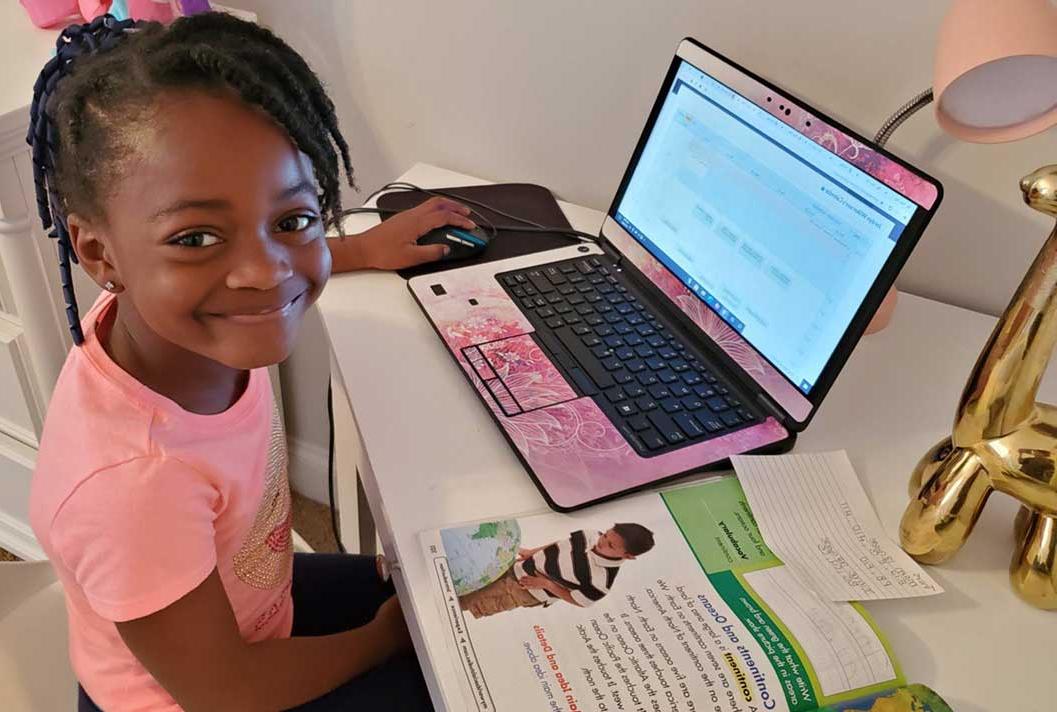 Young student in a pink shirt smiling during their online studies at Connections Academy